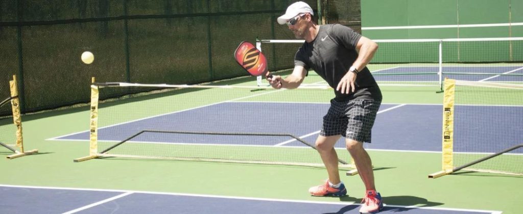 Doubles Pickleball Strategy - a player is standing near the baseline in pickleball 1024x420